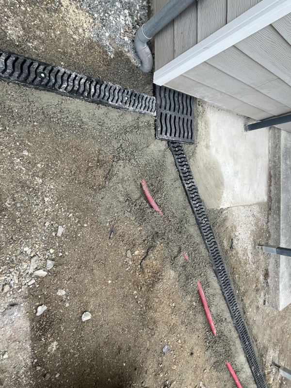 Pose de caniveaux grille fonte 100mm et d'un regard de canalisation des eaux pluviales avec grille fonte dans une cour réalisé par l'entreprise TCTP