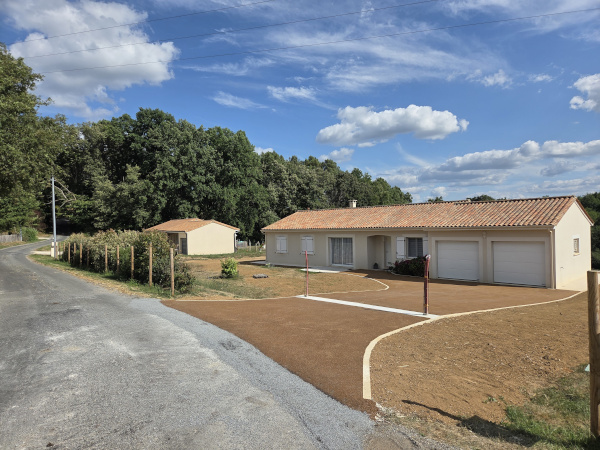 Réalisation d'enrobés beige d'enrochement et de béton désactivé pour aménager les espaces autour de cette maison