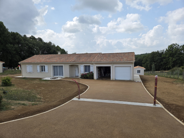 Réalisation d'enrobés beige d'enrochement et de béton désactivé pour aménager les espaces autour de cette maison