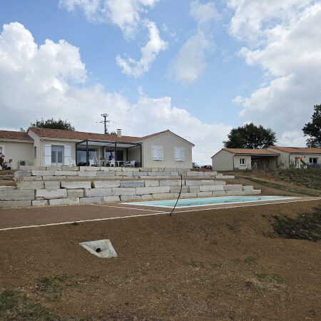 Réalisation par l'entreprise TCTP d'enrobés beige d'enrochement et de béton désactivé pour aménager les espaces autour de cette maison