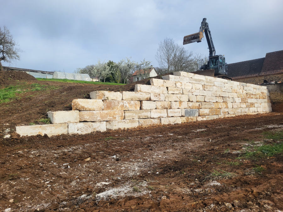 Mise en œuvre avec une pelleteuse Kobelco Blade runner ED160BR de blocs d 'enrochement en pierre de Montagnac d'Auberoche par l'entreprise TCTP en Dordogne 24 pour le soutien d'une plate forme
