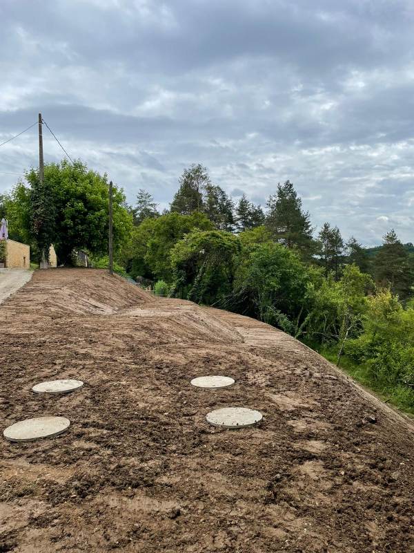 Mise en œuvre par l'entreprise SARL TCTP en Dordogne de remblai et de terre végétale d'apport dans un talus pour la création de petites plates formes dans le but de faciliter l'entretient avec la pose de fosse béton pour la récupération d'eau de pluie.